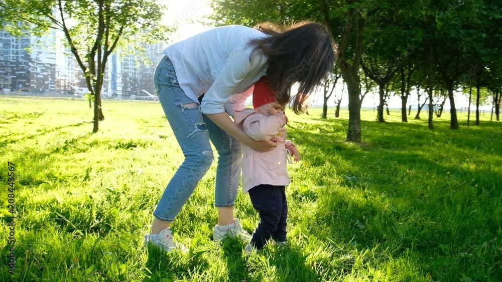 Young mother walking with baby in the park at sunset, slow motion. Young mother walking with baby in the park at sunset, slow motion.