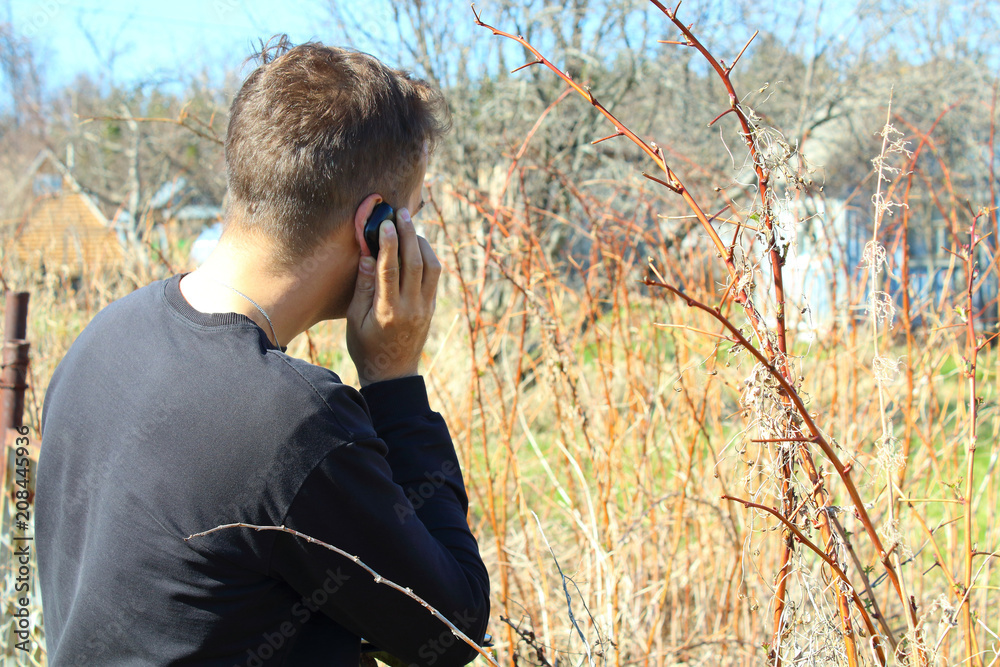 Young man talking on mobile phone in nature. Close-up. Young man talking on mobile phone in nature. Close-up.
