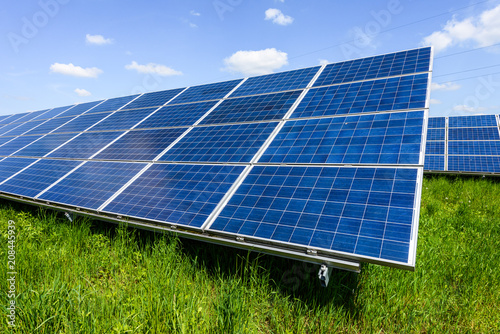 Solar panel on blue sky background. Green grass and cloudy sky. Alternative energy concept photo