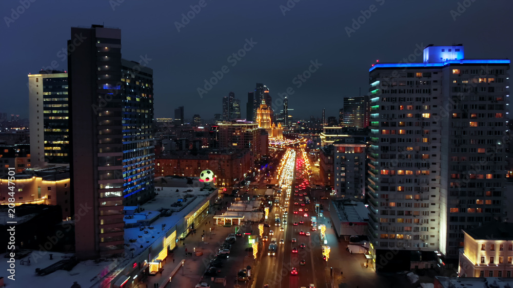 Bright lights of night Moscow from bird's eye view. Intensive traffic at New Arbat street in the heart of the city. Multistory houses illuminated with neon lights on the sides of the wide avenue.
