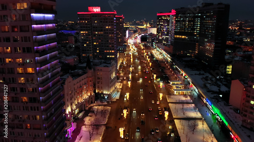 Fototapeta Naklejka Na Ścianę i Meble -  Bright lights of night Moscow from bird's eye view. Intensive traffic at New Arbat street in the heart of the city. Multistory houses illuminated with neon lights on the sides of the wide avenue.