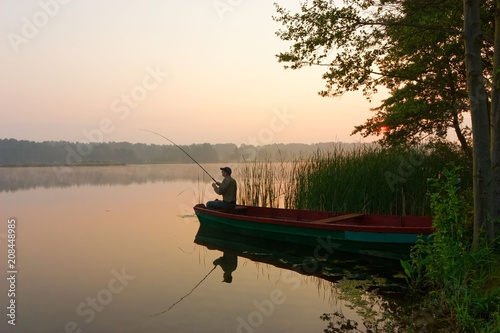 Fisherman catching the fish from wooden boat during sunrise.