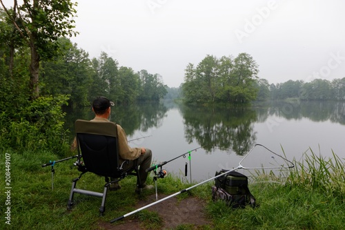 Fisherman sitting on the chair and fishing during cloudy day