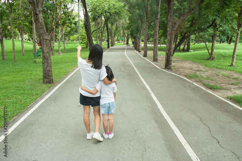 Woman and child walking on footpath and walkway in the public park and feeling happiness and enjoy. © Angkana