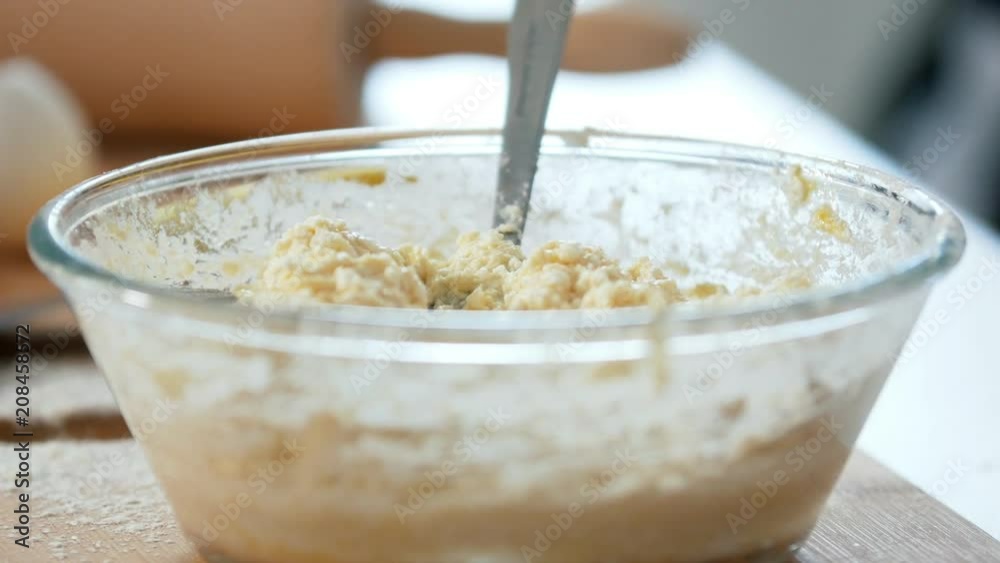 Female hands mixing the dough with a fork in the glass bowl Female hands mixing the dough with a fork in the glass bowl