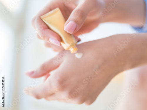 Women s hands with pink manicure applying cream. The concept of skin care