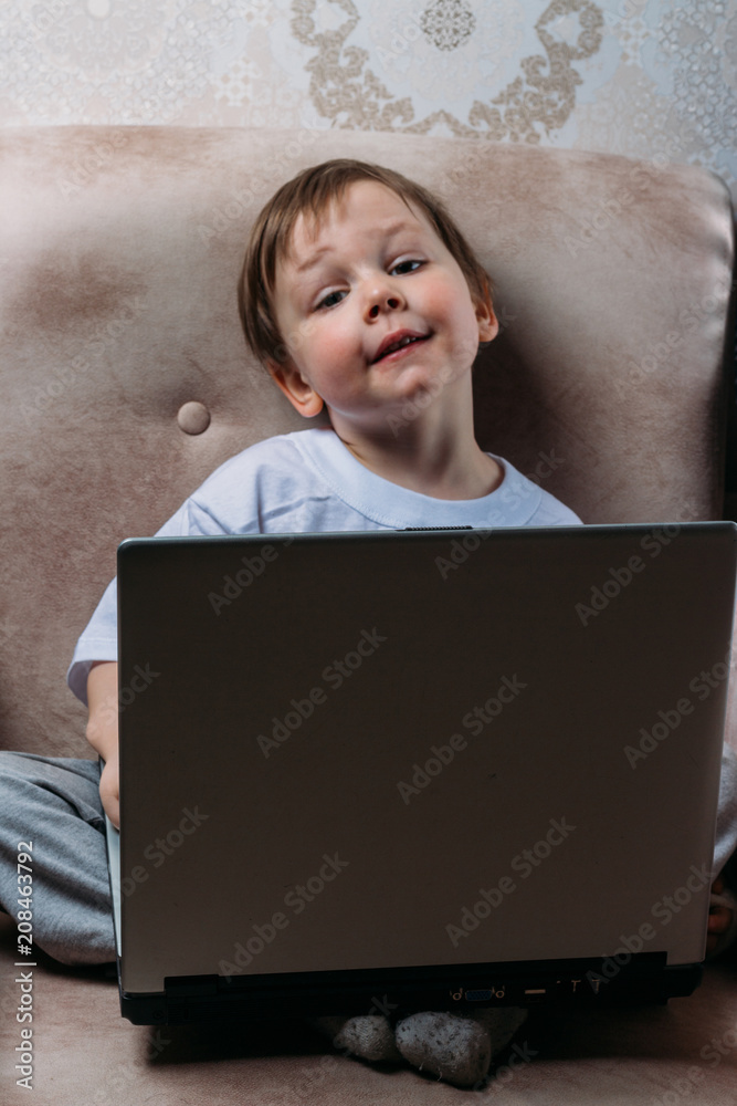 the boy is sitting on a chair and is holding a laptop the boy is sitting on a chair and is holding a laptop