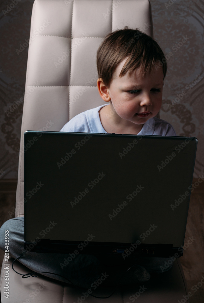 the boy is sitting on a chair and is holding a laptop the boy is sitting on a chair and is holding a laptop