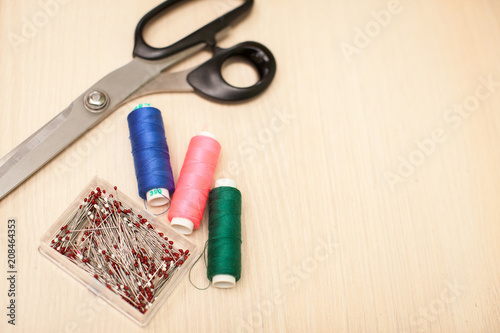 On the cutting table lie scissors, thread and pins. Work place of seamstress. topp view, place for text