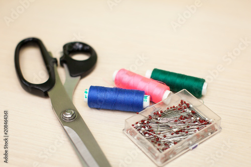 On the cutting table lie scissors, thread and pins. Work place of seamstress. topp view, place for text photo