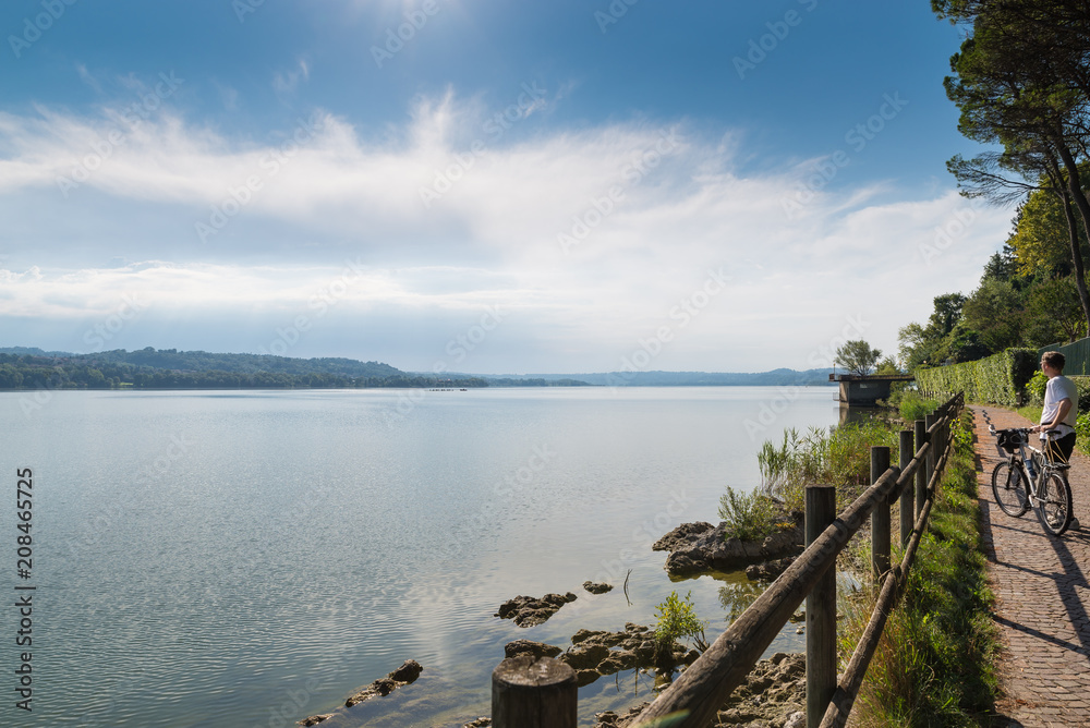 Lake Varese, summer landscape, Italy. Lake, cyclist and cycle - pedestrian track that runs along the lake, place frequented for various activities such as fishing, rowing, walking and cycling
