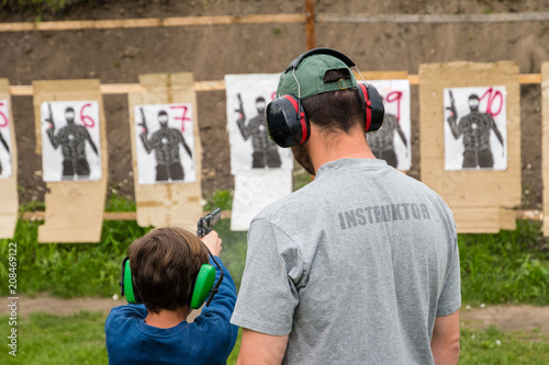 Gun instructor teaching young kid at shooting range