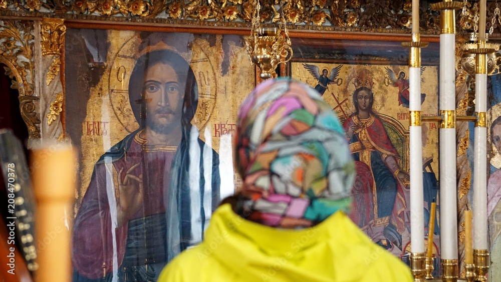 Kambos, Tinos island / Greece – 05.11.2015: a young girl in a colorful scarf in the Orthodox Church of St. Catherine