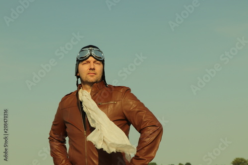 Vintage pilot with leather cap, scarf and aviator glasses  - Portrait of a man in historical pilot clothing © Riko Best