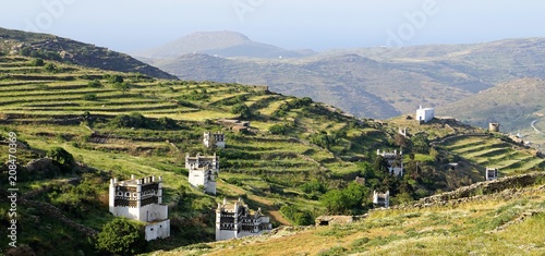 Panoramic spring landscape with famous traditional decorated dovecotes and hedges on the Tinos island and sea in the background, Greece photo