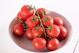 red ripe tomatoes in white bowl on white background with water drops condentation moisture 