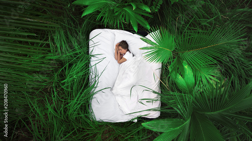 A hidden place. Sleeping woman in deep jungle forest lies on airbed,View from above photo
