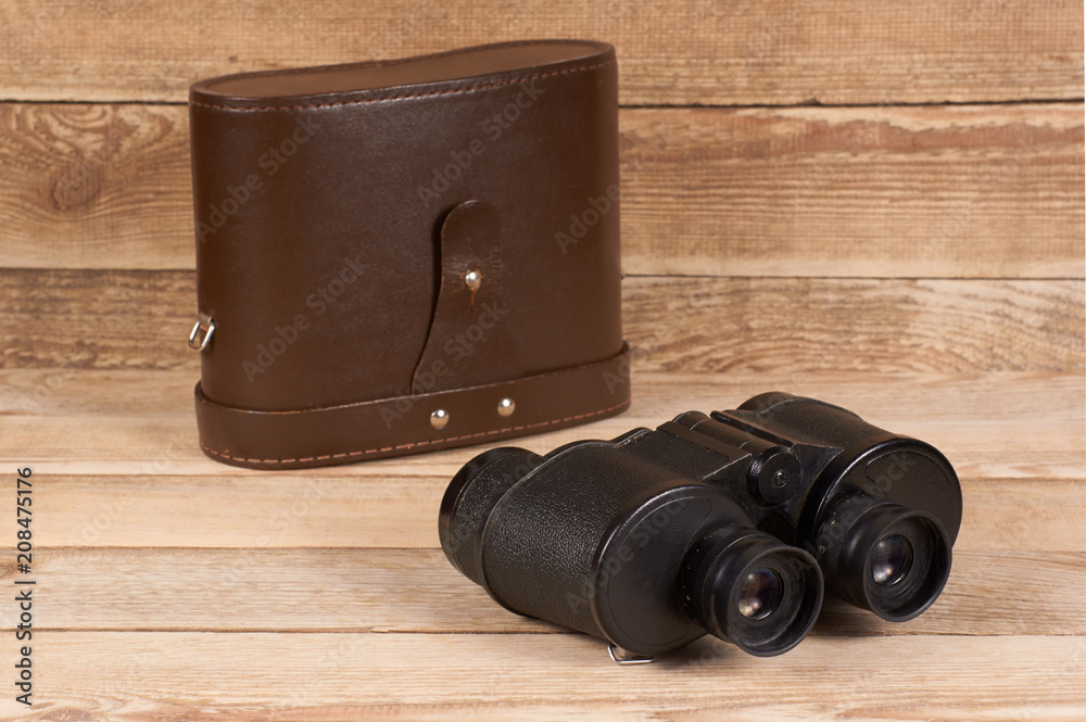 Old army binoculars with a case on a wooden background