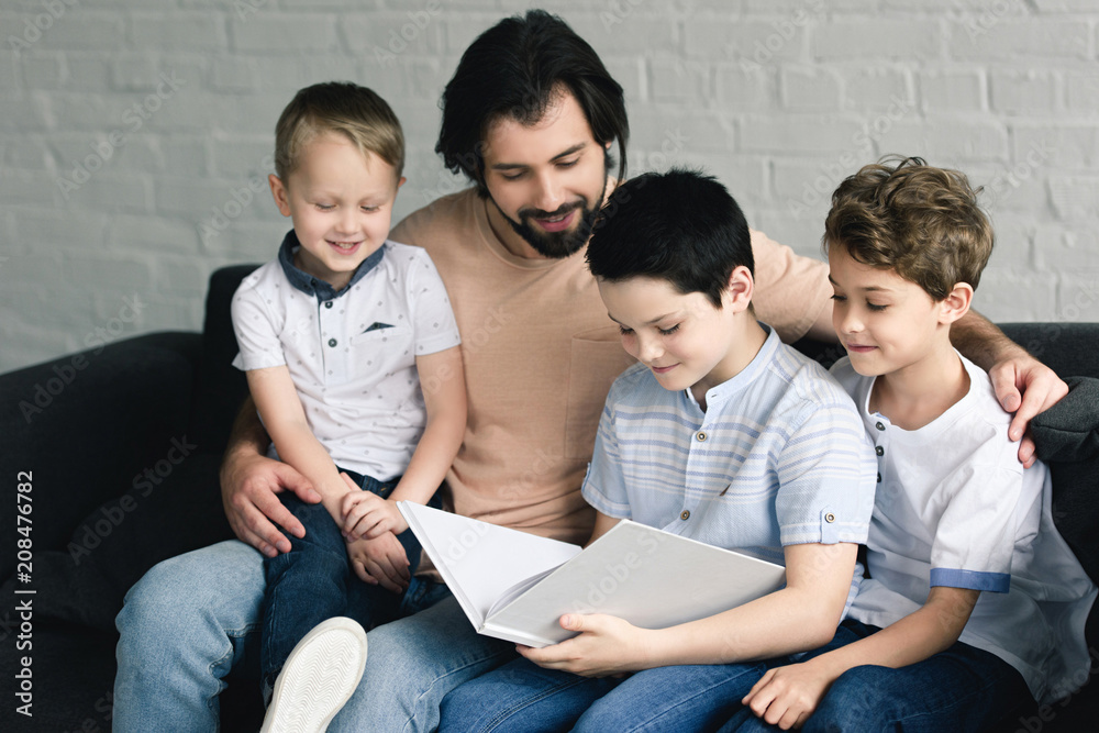 portrait of father and sons reading book together at home portrait of father and sons reading book together at home