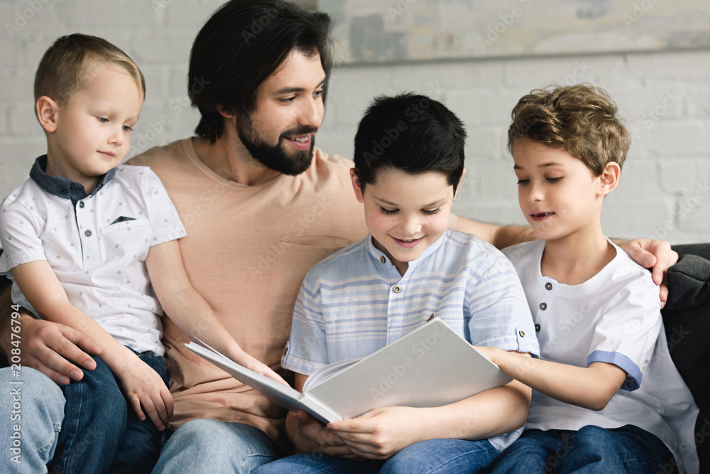 portrait of father and sons reading book together at home portrait of father and sons reading book together at home