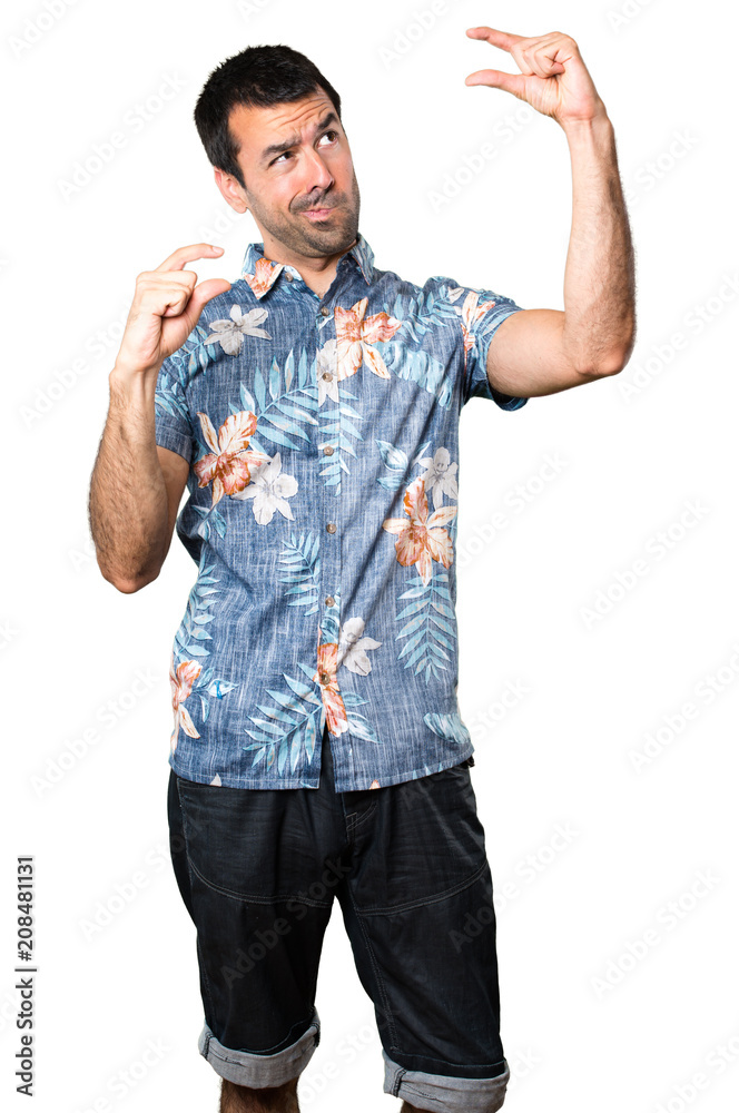 Handsome man with flower shirt making tiny sign on isolated white background Handsome man with flower shirt making tiny sign on isolated white background