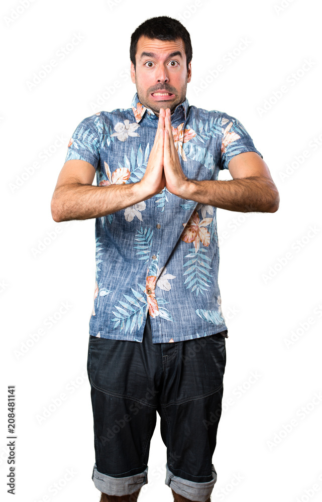 Handsome man with flower shirt pleading on isolated white background Handsome man with flower shirt pleading on isolated white background