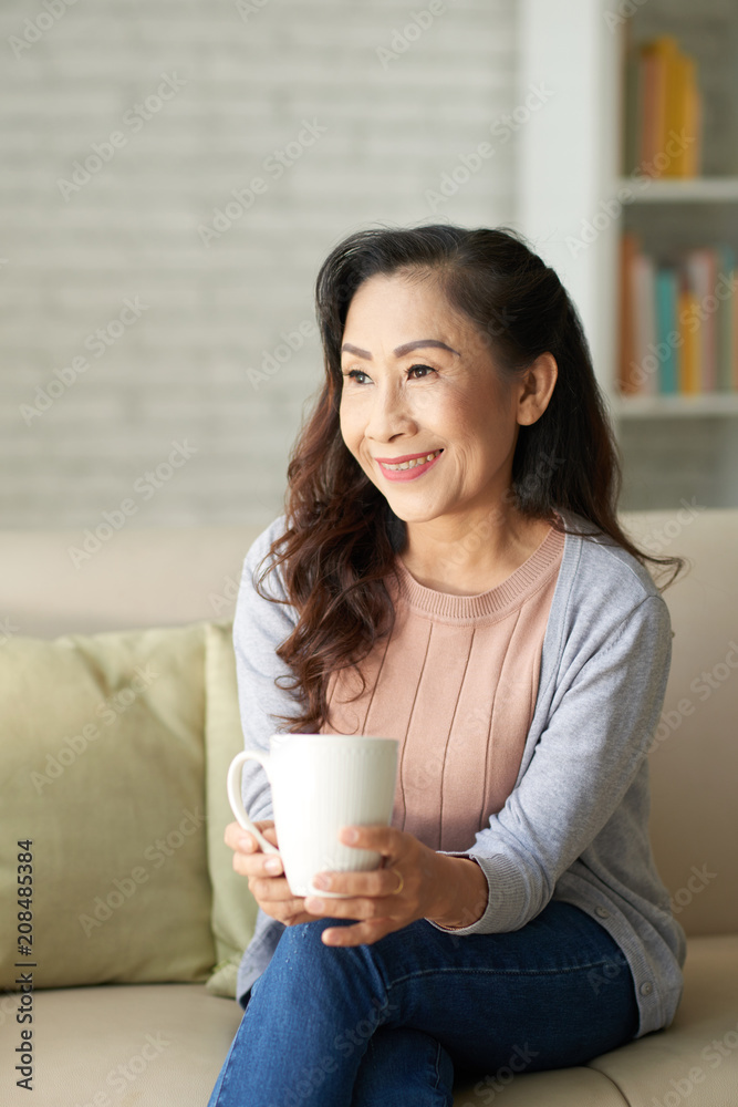 Happy elderly woman sitting with cup of coffee at home Happy elderly woman sitting with cup of coffee at home