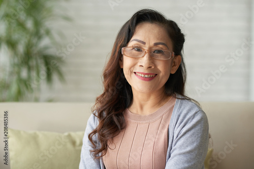 Portrait of Asian smiling mature woman sitting at home