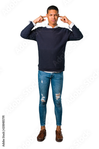 Young african american man covering both ears with hands. Frustrated expression on isolated white background