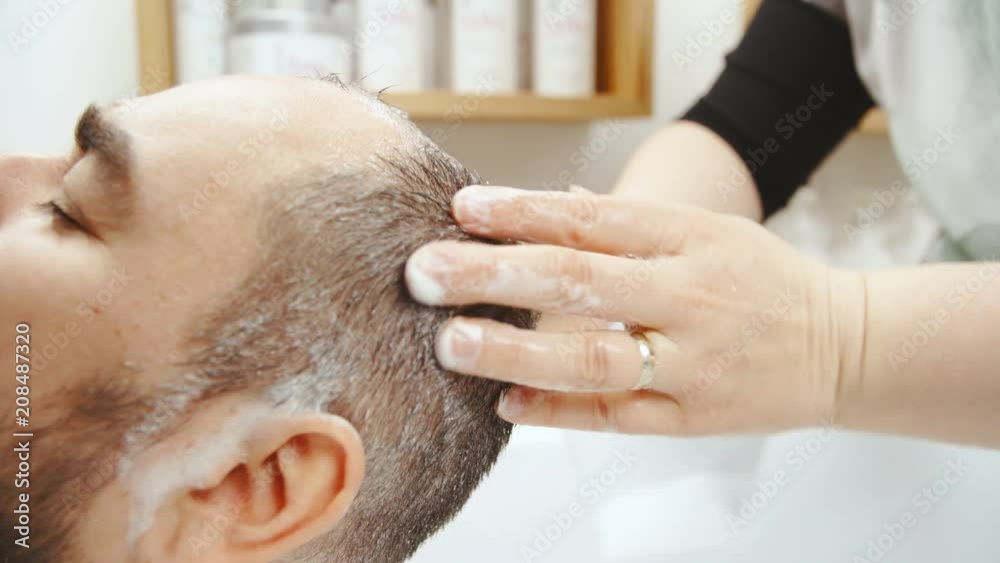 Male head shampooing at hairdresser in slow motion close-up 4K. Side view of man hair in focus while another person hands shampooing inside the sink at hairdressers salon. Male head shampooing at hairdresser in slow motion close-up 4K. Side view of man hair in focus while another person hands shampooing inside the sink at hairdressers salon.