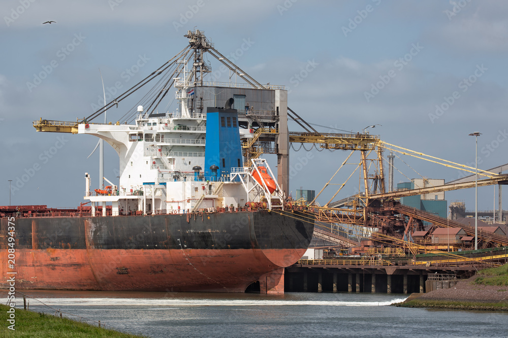 Big steel factory in harbor IJmuiden with cargo carrier in front, The Netherlands