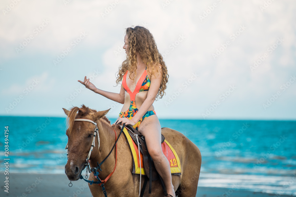 Pretty young lady riding a horse on the beach background of the sea Pretty young lady riding a horse on the beach background of the sea