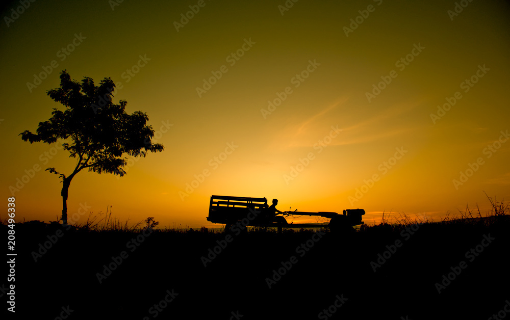 Fototapeta premium Silhouette Farmer driving a tractor in the field. 