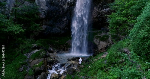 European man with beard is doing waterfall-meditation while standing under big waterfall in austria, wildensteiner waterfall