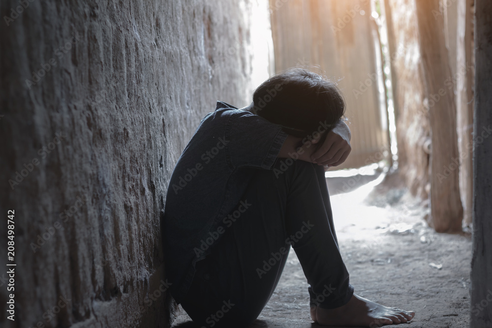 Helpless little girl sitting on floor against old earth brick wall,stop violence and abused children,human trafficking concept