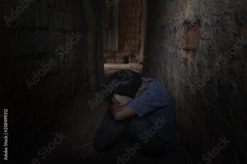 Helpless little girl sitting on floor against old earth brick wall,stop violence and abused children,human trafficking concept