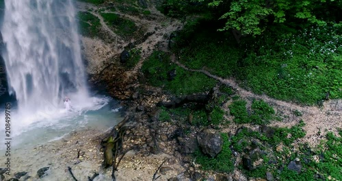 European man with beard is doing waterfall-meditation while standing under big waterfall in austria, wildensteiner waterfall