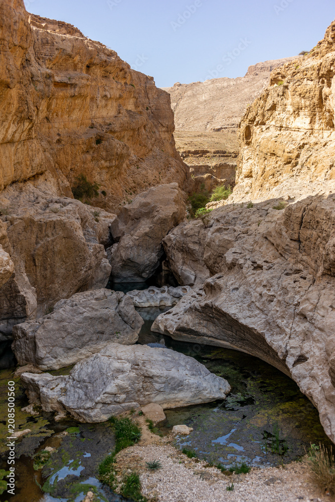A stream of water in the rocky desert of Oman flowing in a canyon to the oasis of Wadi Bani Khalid - 9