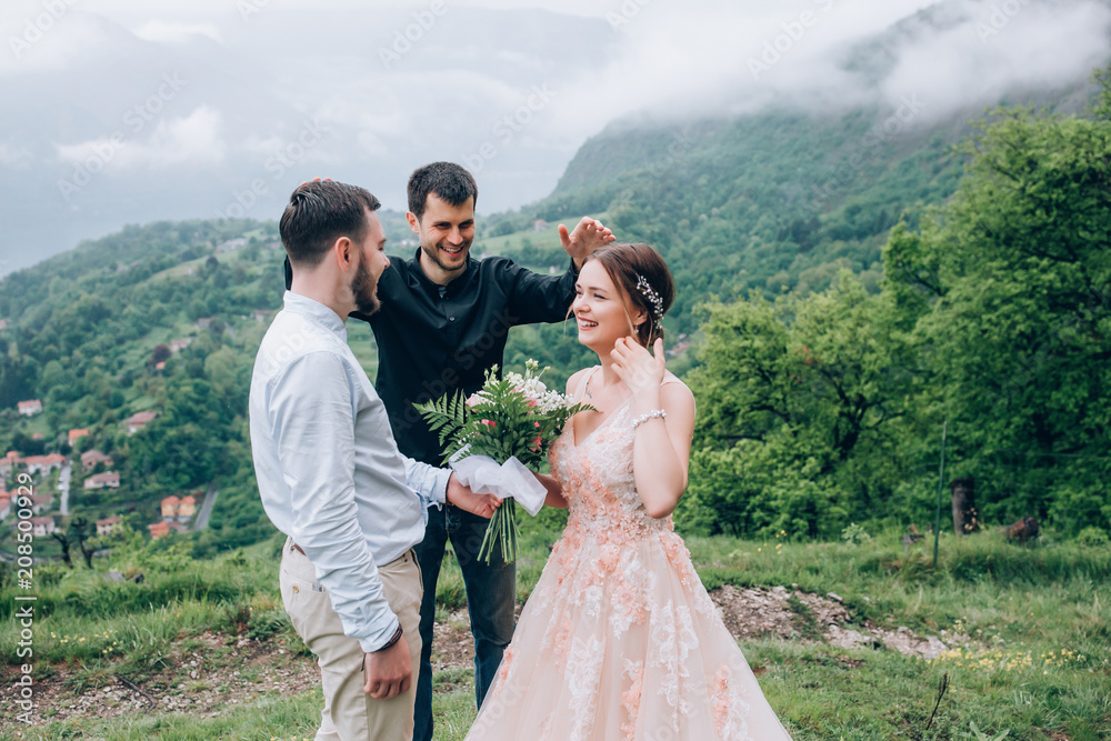 Walking newlyweds in nature. Groom and bride against the background of mountains and the sea. The priest blesses the young.