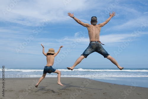 ビーチでジャンプする父と子供