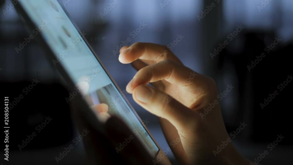 In this close up type of shot you can see young woman holding Apple Ipad touch screen tablet device in her hands. She is scrolling the screen while searching for pictures or reading news feed online.