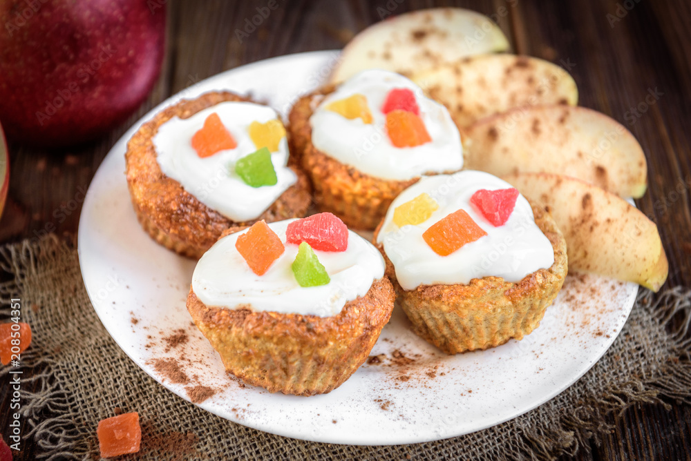 Oat muffins with yogurt, candied fruit, red apple and cinnamon on dark wooden background. Oat muffins with yogurt, candied fruit, red apple and cinnamon on dark wooden background.