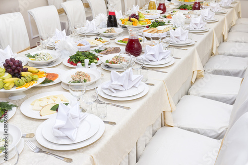 served festive dining table with dishes on plates, chairs, vegetables, fruits, greens, food