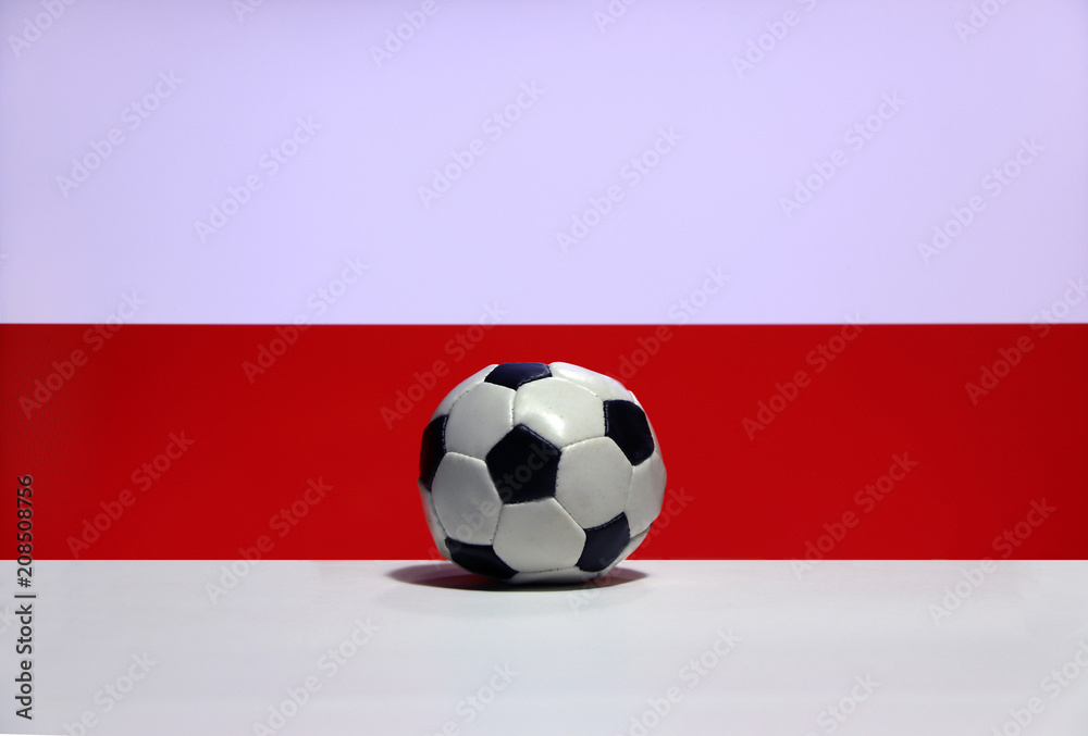 Small football on the white floor and Polish nation flag with white and red background. The concept of sport. Small football on the white floor and Polish nation flag with white and red background. The concept of sport.