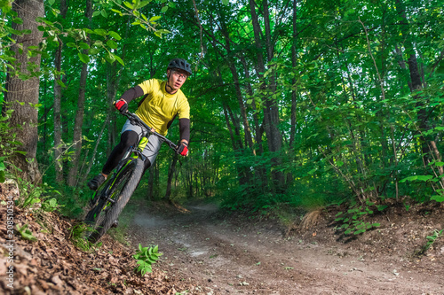 A mountain biker rides the slope in the forest.