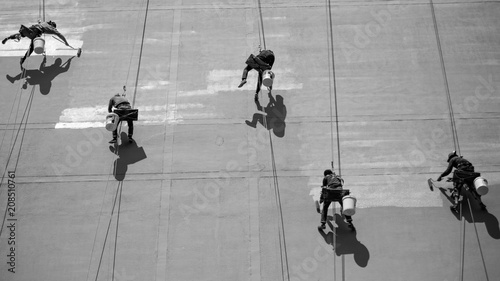Photography 5 workers painting a skyscraper in bangkok thailand, hanging from ropes