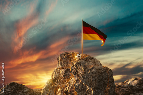 3d rendering of waving German flag next to the soccer ball on rocky landscape in the beautiful sunset