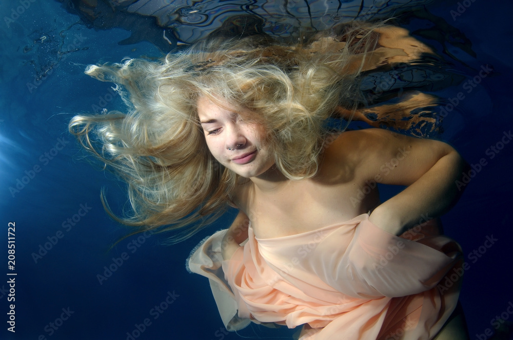 Young beautiful woman in a long dress underwater