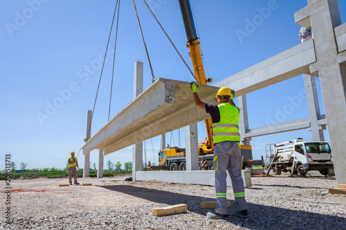 Workers are helping crane from the ground, keep balance and direction
