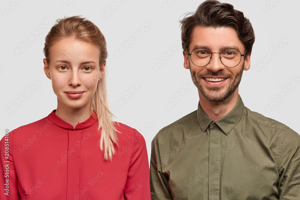 Photo of lovely young female in red blouse meets with her older brother, feels support near his strong shoulder, pose together against white background. Glad young male professor with student Photo of lovely young female in red blouse meets with her older brother, feels support near his strong shoulder, pose together against white background. Glad young male professor with student